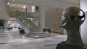 Un hall d’entrée moderne avec un escalier, une grande sculpture et un espace détente.