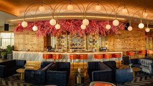 Un espace bar avec un mur en bois, un comptoir et des sièges comprenant des tables rondes et des canapés.