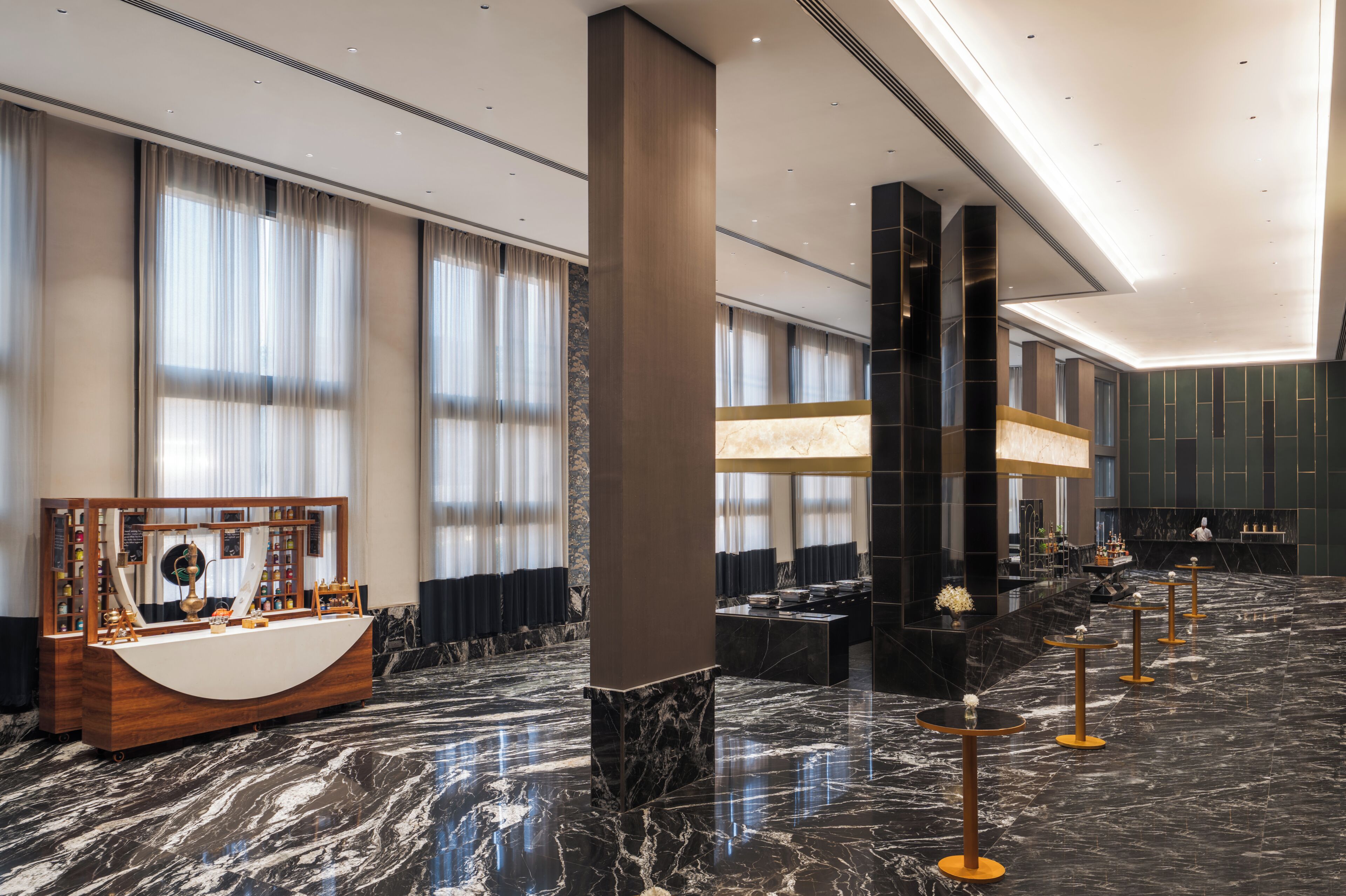 A spacious lobby with a marble floor, a reception desk, and a seating area with tables and chairs.
