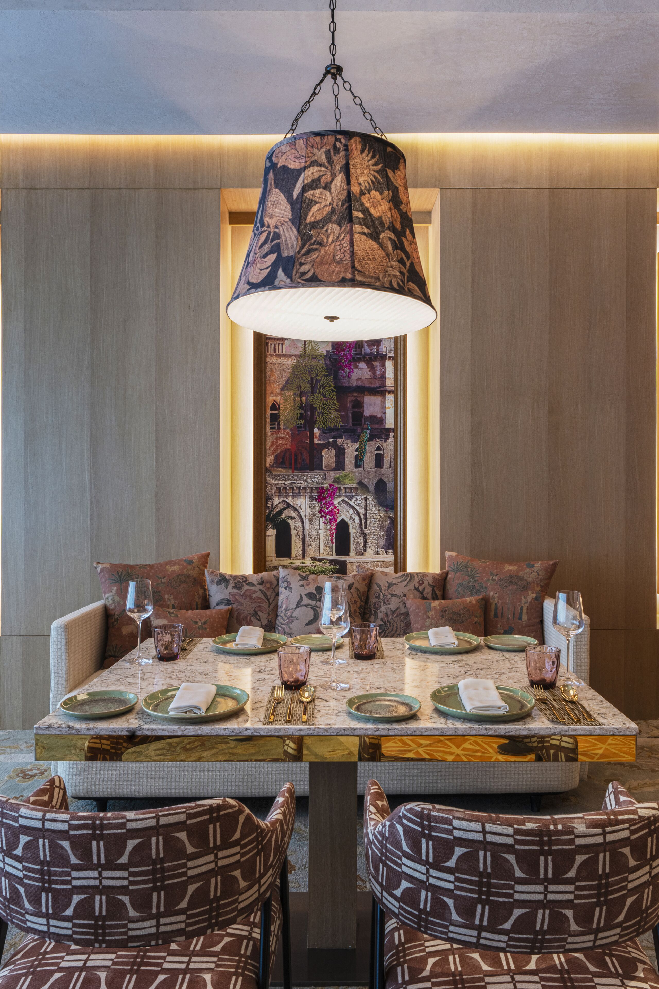Un comedor con una mesa grande dispuesta para cuatro personas, rodeada de sillas con un estampado.