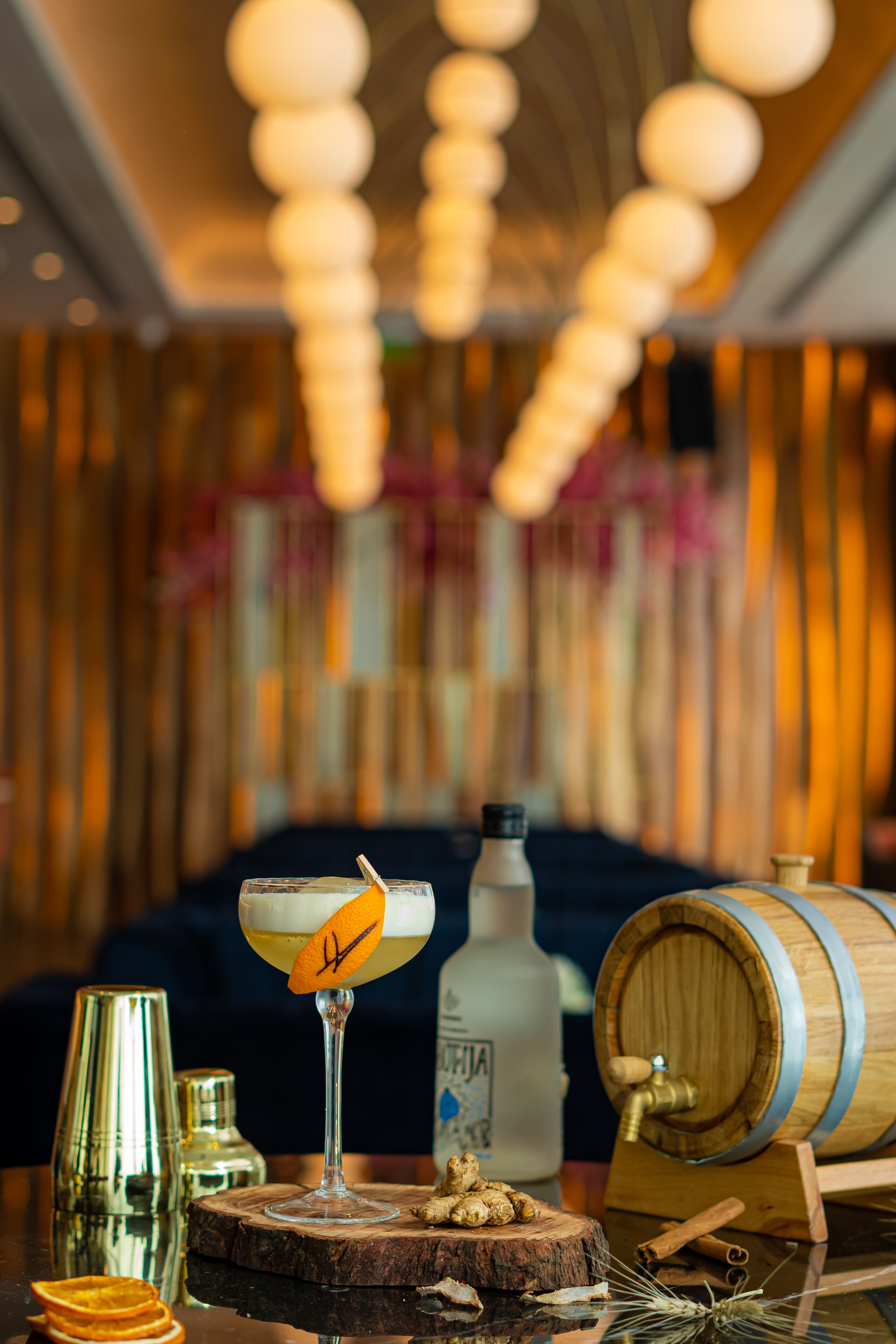 A bar setting with a cocktail glass, a bottle, and a wooden barrel.