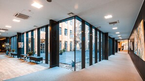 Un interior moderno con separadores de vidrio, suelo de madera y vista a un edificio de ladrillo.