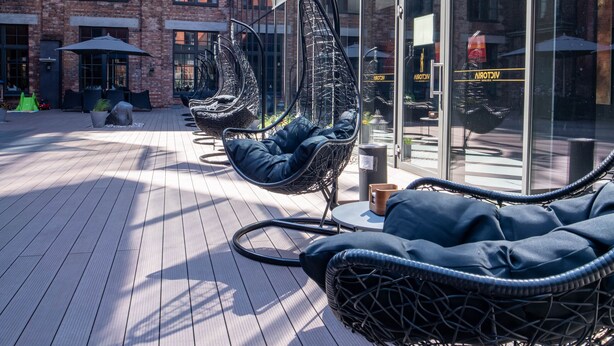 Una terraza en la azotea con sillas de mimbre y un piso de madera.