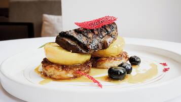 Un plato de comida con filete, patatas y aceitunas.