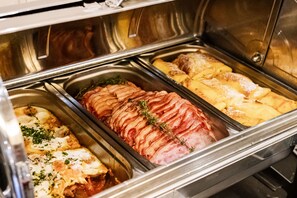 A buffet with various dishes including sliced ham, potatoes, and a casserole. - Victoria hotel Kaunas (Kaunas)