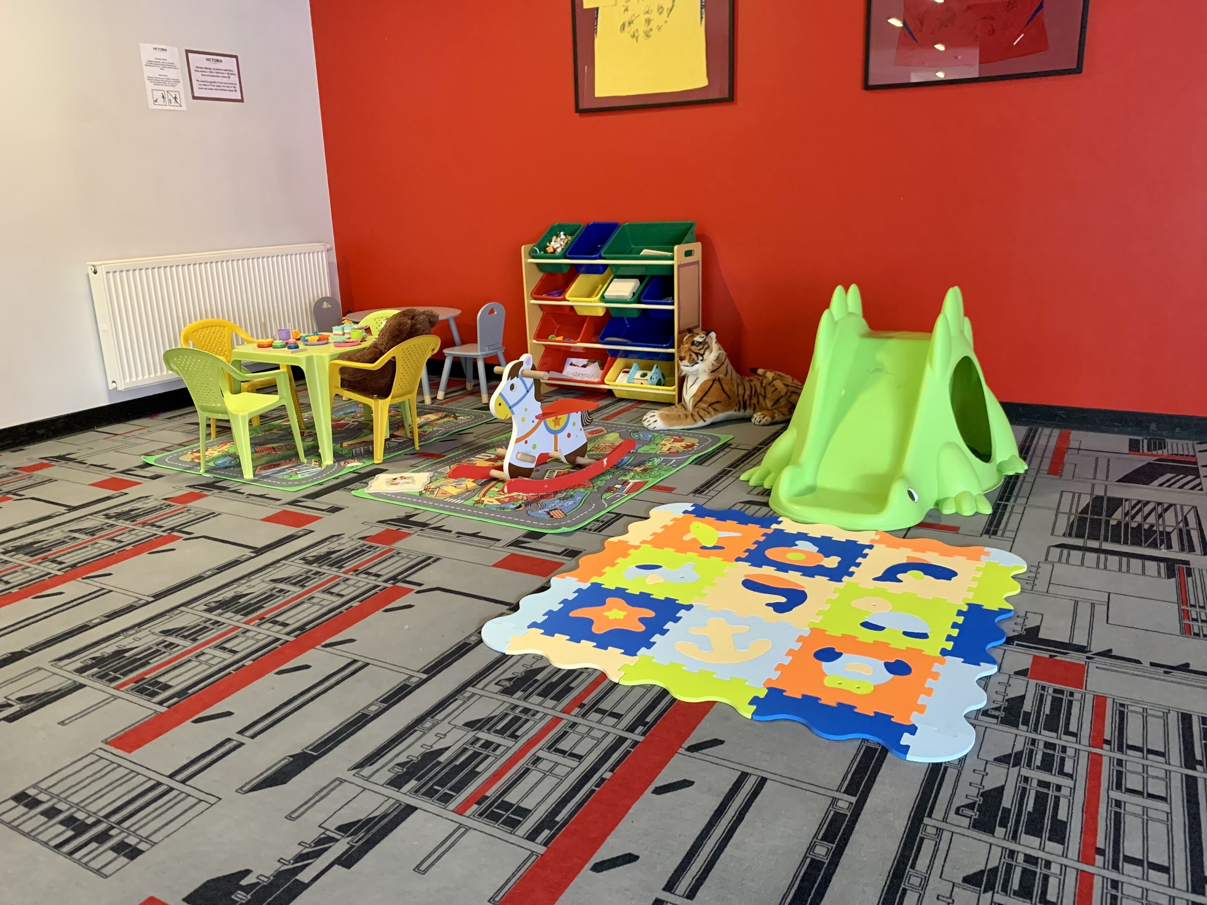 A playroom with a mat puzzle, a green play tent, and a tiger plush toy.