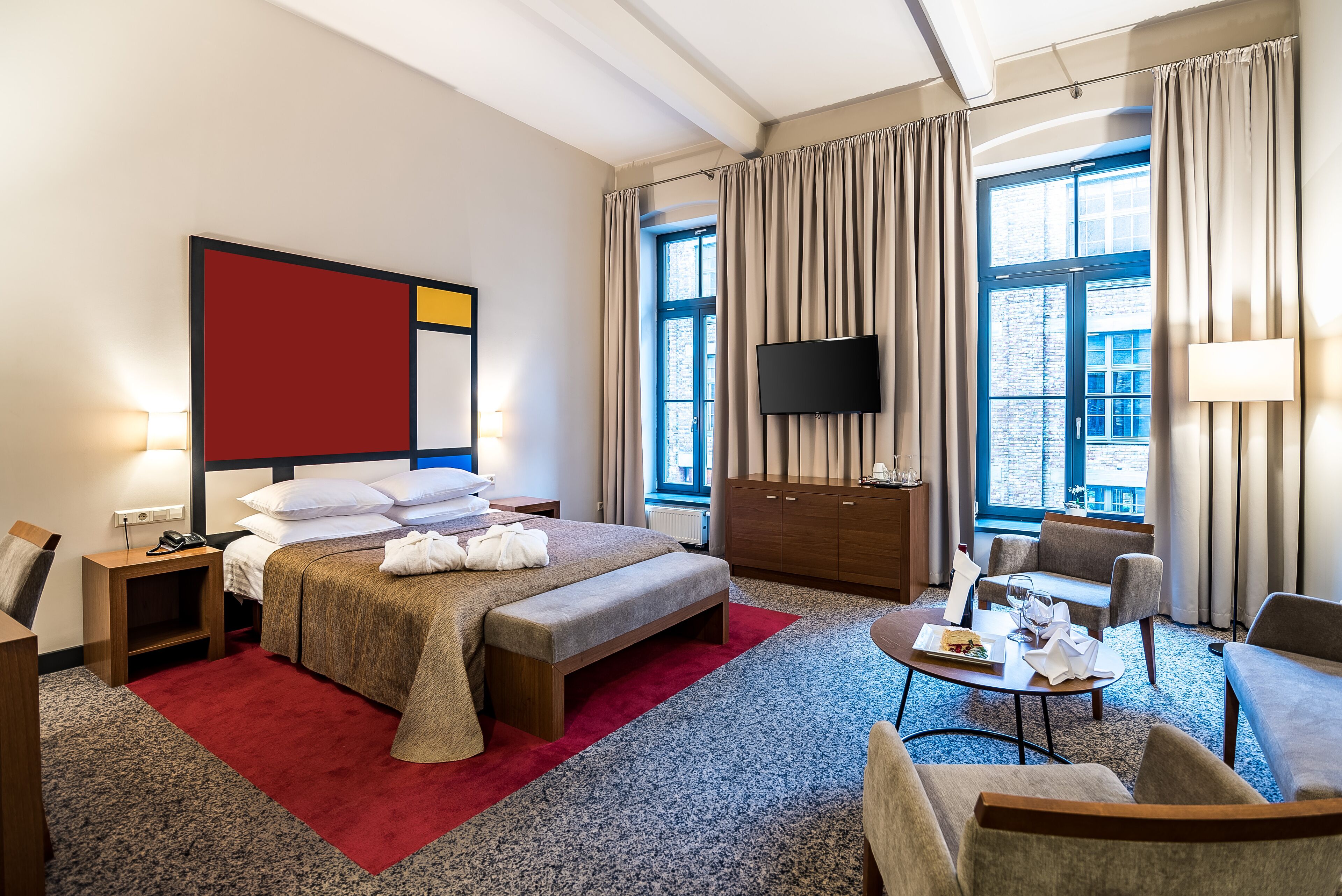 Habitación de hotel con cama, escritorio, televisor, ventana y vistas a la ciudad.