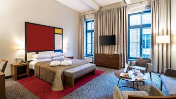 Habitación de hotel con cama, escritorio, televisor, ventana y vistas a la ciudad.