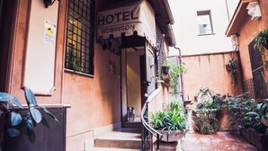 A hotel entrance with a sign reading "HOTEL ROBINSON," a staircase, and potted plants. - Hotel Robinson (Rome)