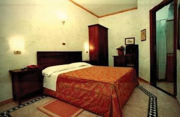 Une chambre à coucher avec un lit, une table de chevet, une armoire et un miroir.