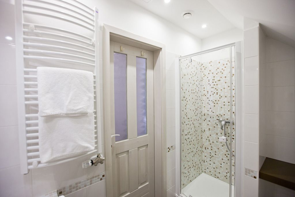 Ein Badezimmer mit weißer Tür, einem Handtuchhalter und einer Dusche mit Mosaikfliesen.