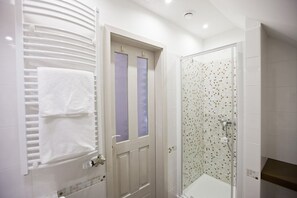 A bathroom with a white door, a towel rack, and a shower with mosaic tiles. - Tornácos Panzió (HEGYKÖ)