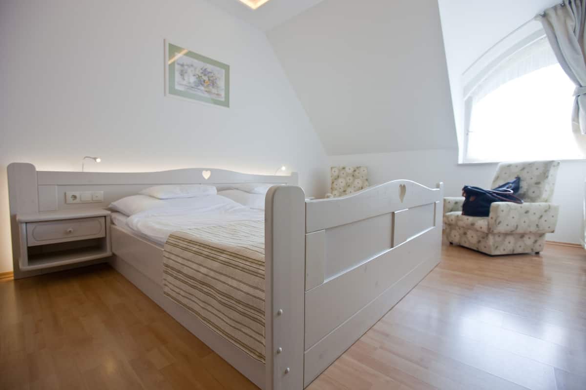 Un dormitorio con cama, mesita de noche y una silla.