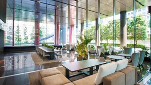 A spacious lobby with high ceilings, large windows, and modern furniture.