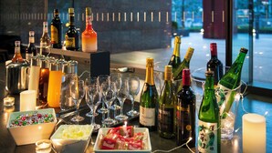 A bar area with various bottles of alcohol, glasses, and small bowls of snacks.