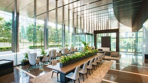 A modern conference room with a long table, chairs, and potted plants.