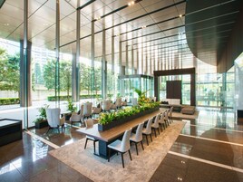 A modern conference room with a long table, chairs, and potted plants.
