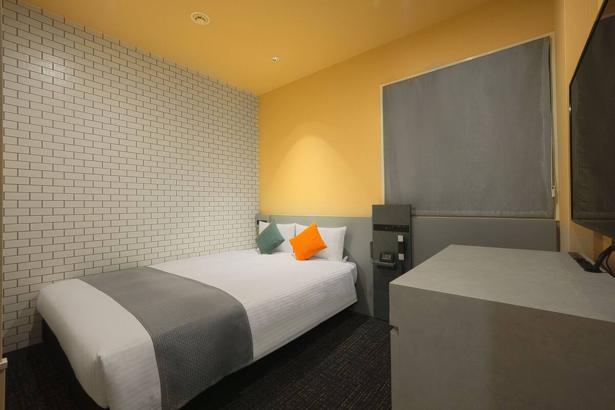 A hotel room with two beds, a desk, and a television.