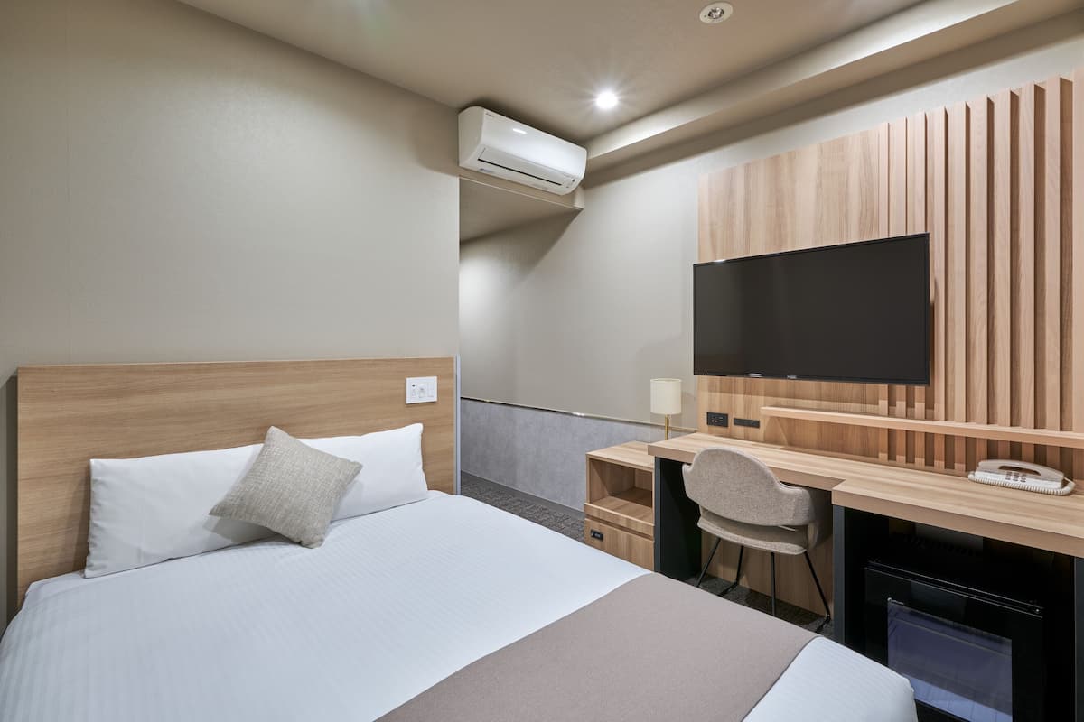 Habitación de hotel con cama, escritorio, silla, televisión de pantalla plana y aire acondicionado.