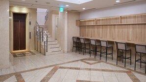 A modern hotel lobby with a marble floor, a staircase, and a bar area with chairs. - Hotel Villa Fontaine Tokyo - Jimbocho (Tokyo)