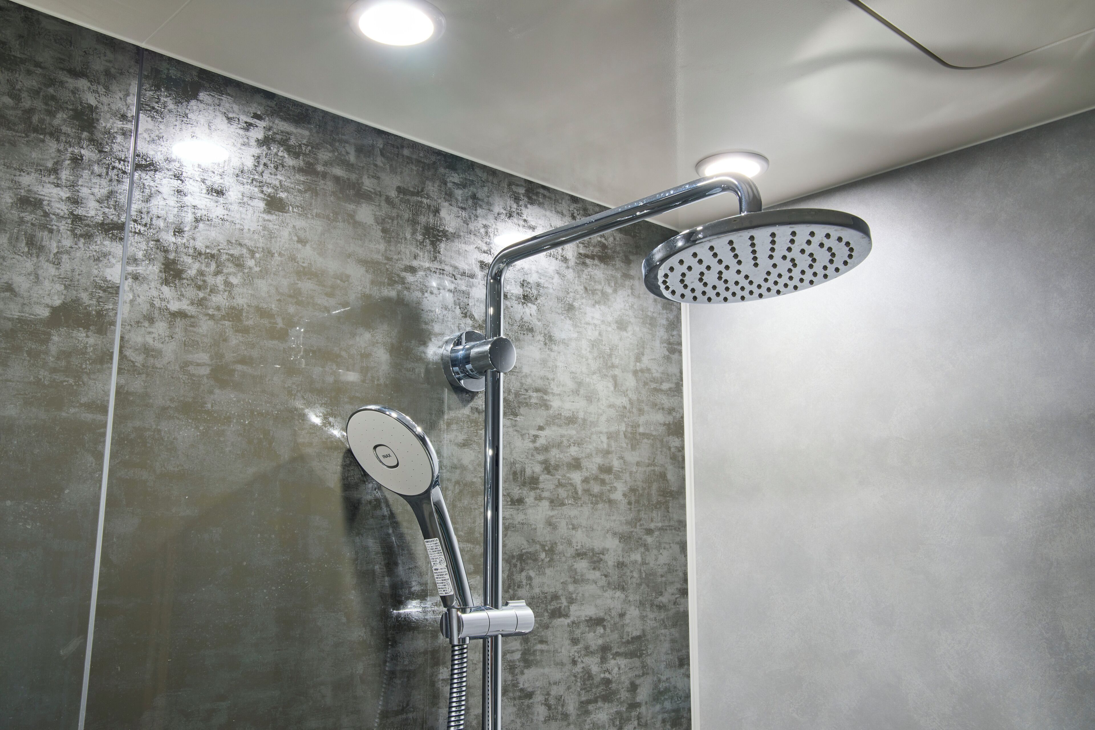 A modern shower with a handheld showerhead and a fixed rain showerhead.