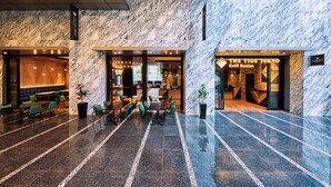 A modern lobby with marble walls and a seating area with tables and chairs. - Hotel Villa Fontaine Grand Tokyo - Shiodome (Tokyo)