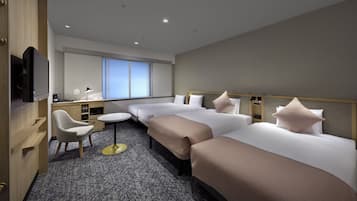 A hotel room with two beds, a desk, a chair, a TV, and a window with blinds.
