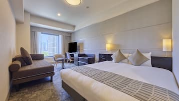 A hotel room with a large bed, a desk, a chair, and a television.