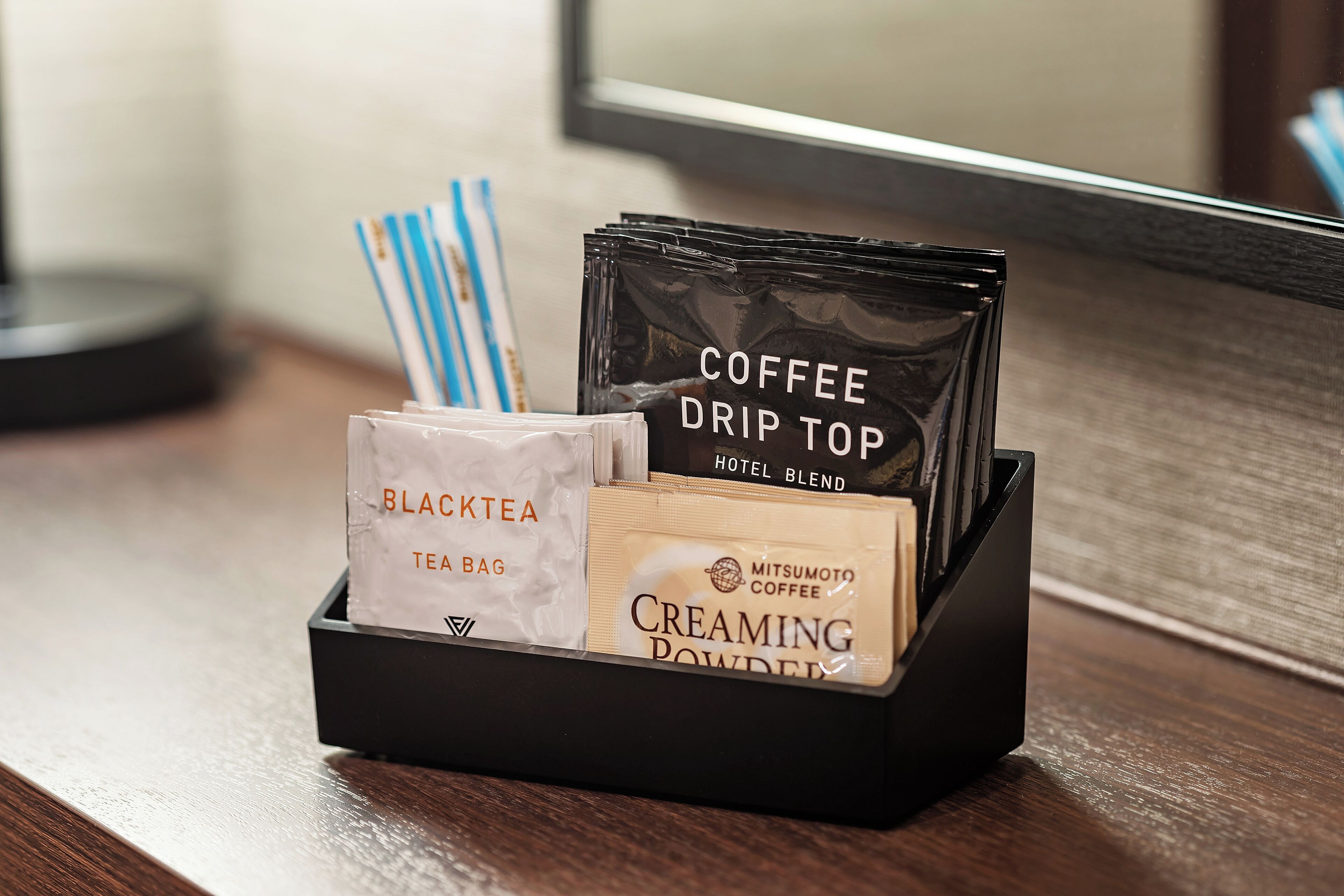 A coffee station with a tea bag, creaming powder, and a coffee drip top.