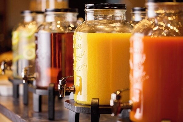Una hilera de dispensadores de bebidas con botellas de vidrio transparente y grifos de metal.