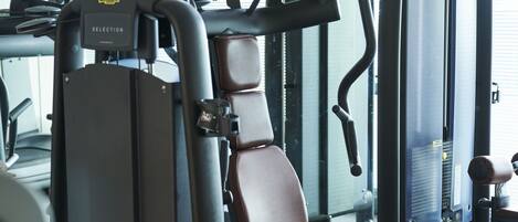 Un gimnasio con equipo de ejercicio, incluyendo una máquina de selección y una máquina de remo.