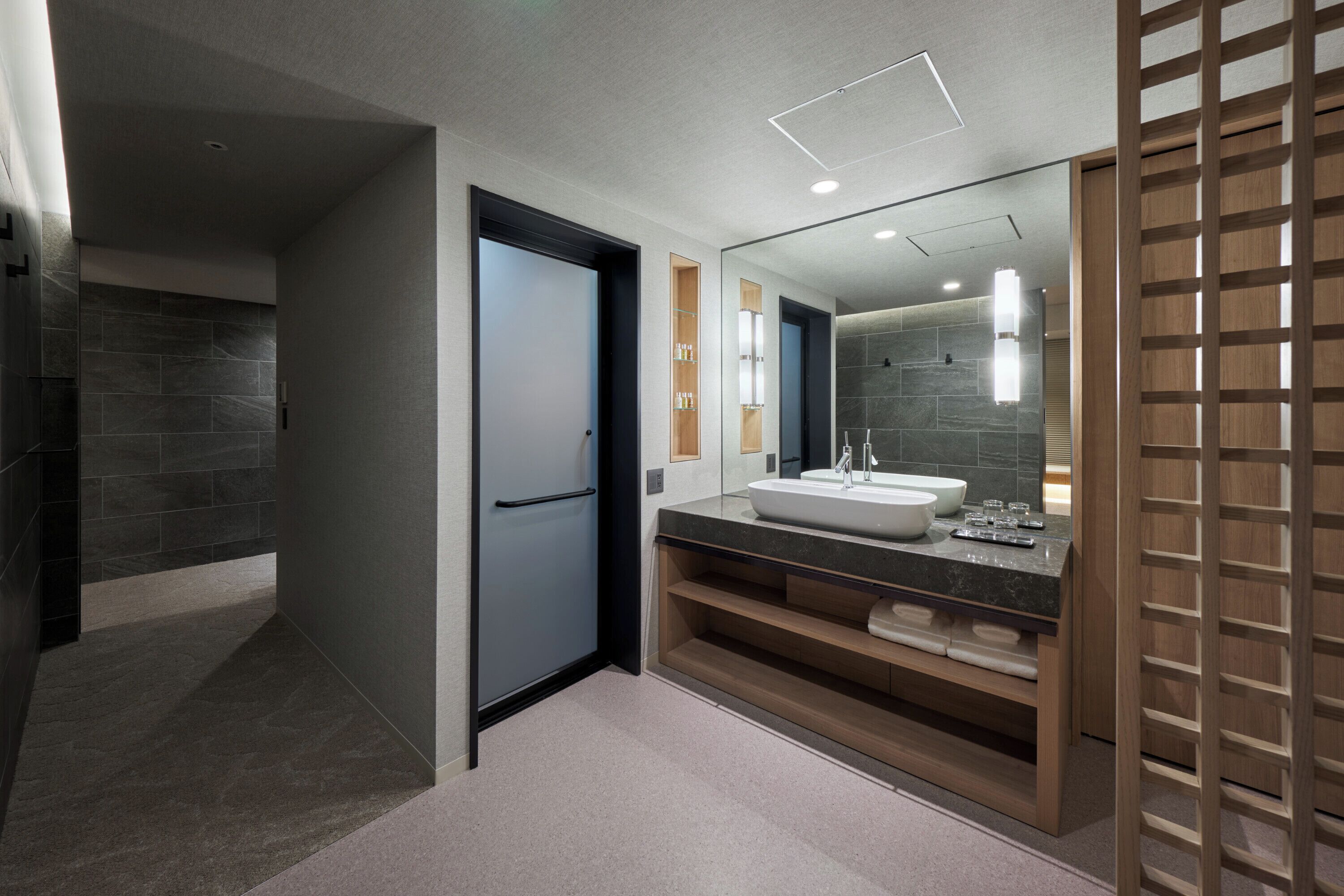 A modern bathroom with a large mirror, a sink, and a shower area.