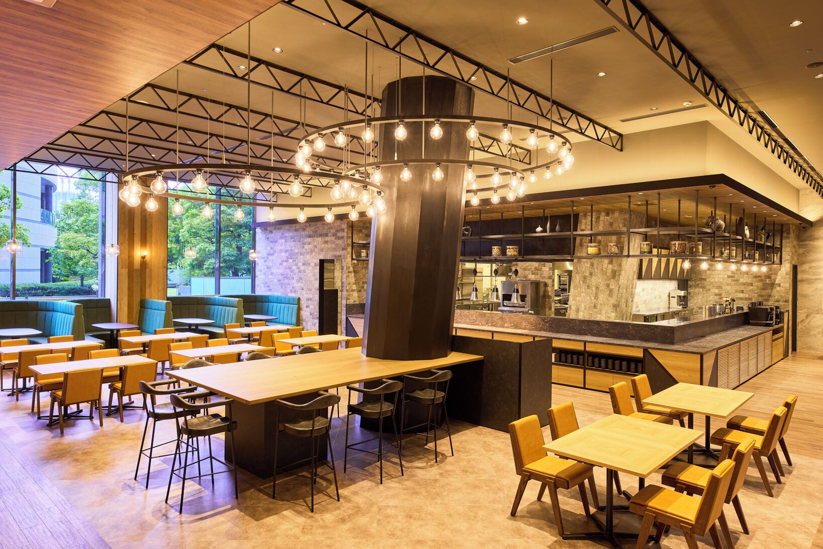 A modern restaurant with high ceilings, exposed beams, and a central light fixture. Tables and booths are arranged for dining.