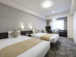 Habitación de hotel con dos camas, un escritorio, un televisor y una ventana con cortinas.