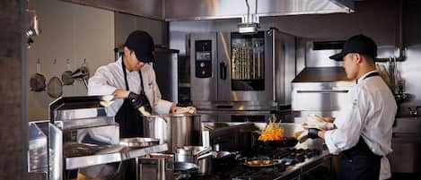 A professional kitchen with stainless steel appliances, a large oven, and chefs preparing food.