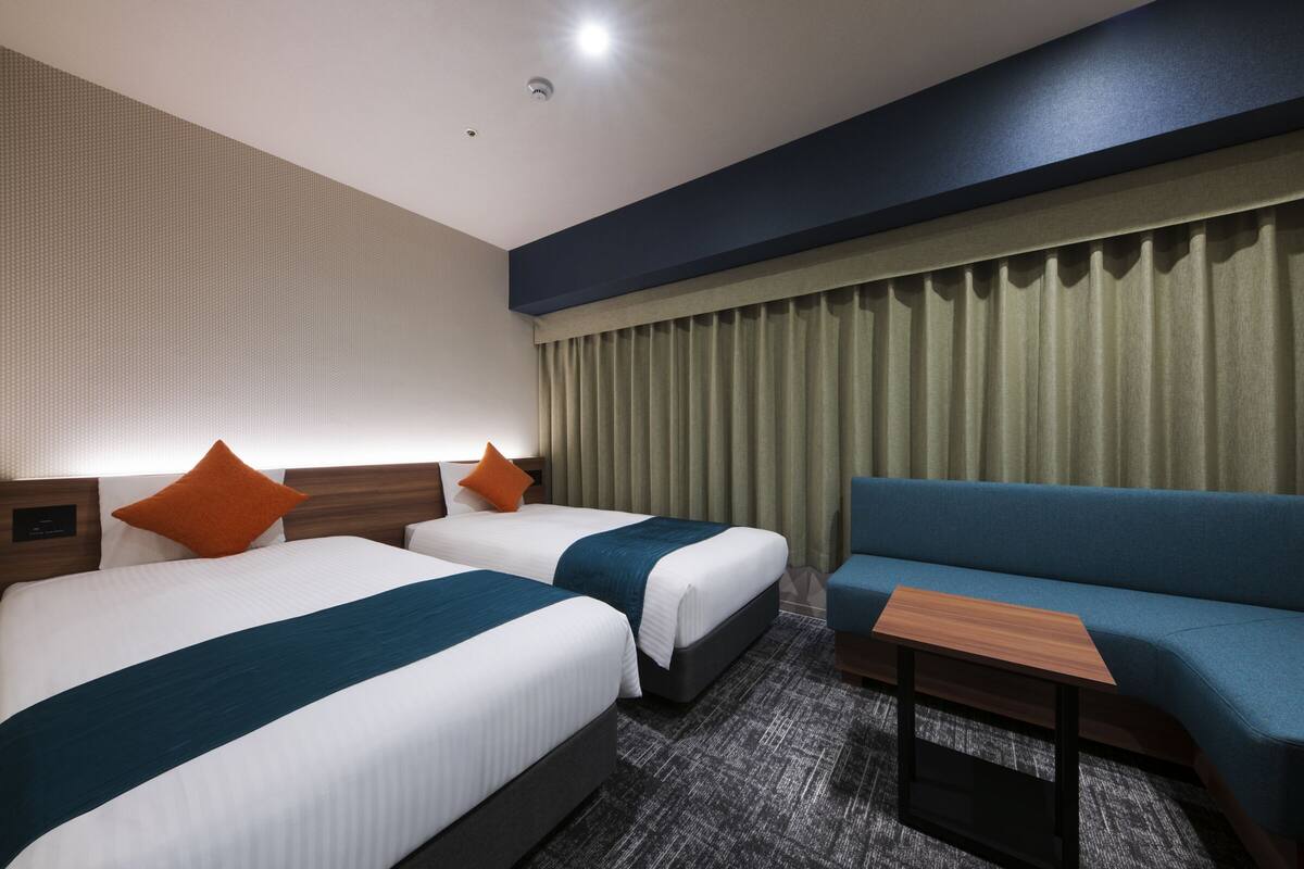 Ein Hotelzimmer mit zwei Betten, einem Schlafsofa und einem kleinen Tisch.