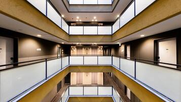 Un atrium à plusieurs niveaux, doté de rampes en verre, d’un éclairage encastré et d’un espace central ouvert.