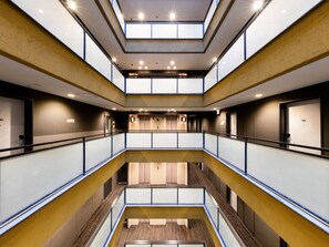 Ein mehrgeschossiges Atrium mit Glasgeländern, eingelassener Beleuchtung und einem offenen Innenbereich.