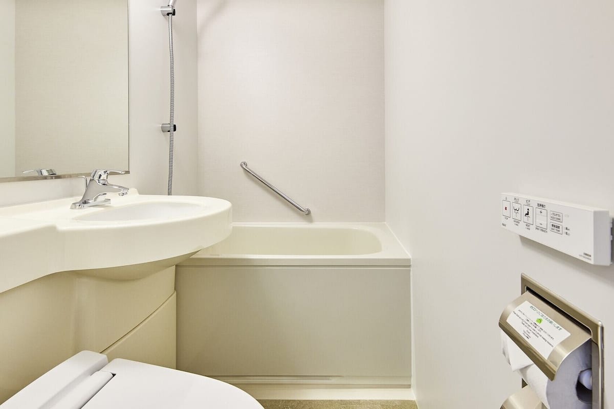 A bathroom with a sink, mirror, shower, and toilet.