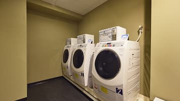 A laundry room with three washing machines, a water heater, and a control panel.