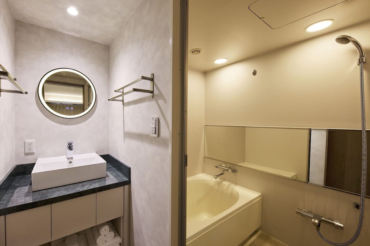 Un baño con lavabo, espejo, toallero y ducha.