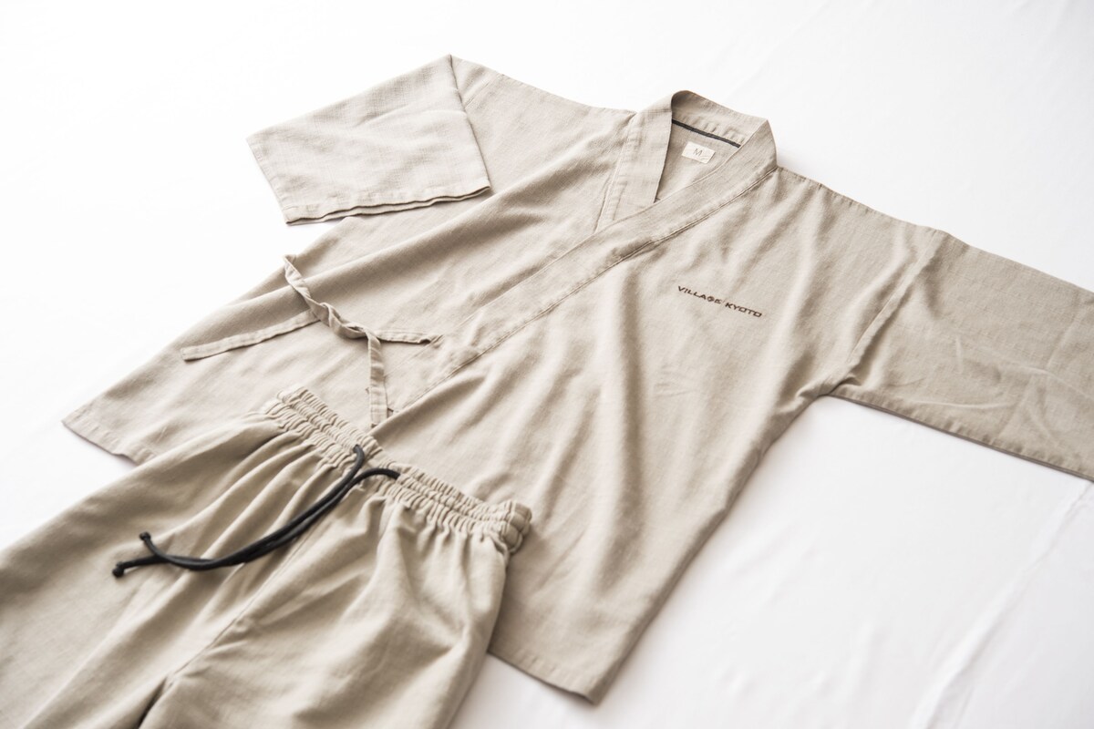 A beige pajama set with a drawstring and a pocket on the front, laid out on a white surface.
