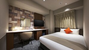 Ein Hotelzimmer mit Bett, Schreibtisch, Stuhl, Fernseher und einem Fenster mit Vorhängen.