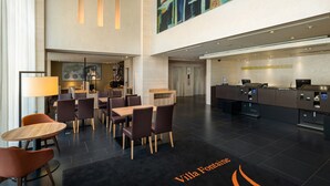 Eine moderne Hotelhalle mit einer Rezeption, einer Sitzecke und einem großen abstrakten Gemälde an der Wand.