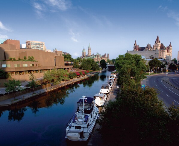 A river with boats docked along the side, a bridge in the background, and buildings on the opposite bank.
