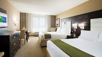 A hotel room with two beds, a desk, a chair, a television, and a window with curtains.