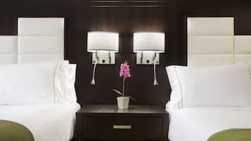A hotel room with two beds, a nightstand with a drawer, and two wall-mounted lamps.