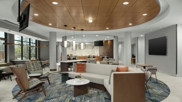 Ein moderner Lounge-Bereich mit einer runden Sitzgruppe, einem Couchtisch in der Mitte und einer Küche im Hintergrund.