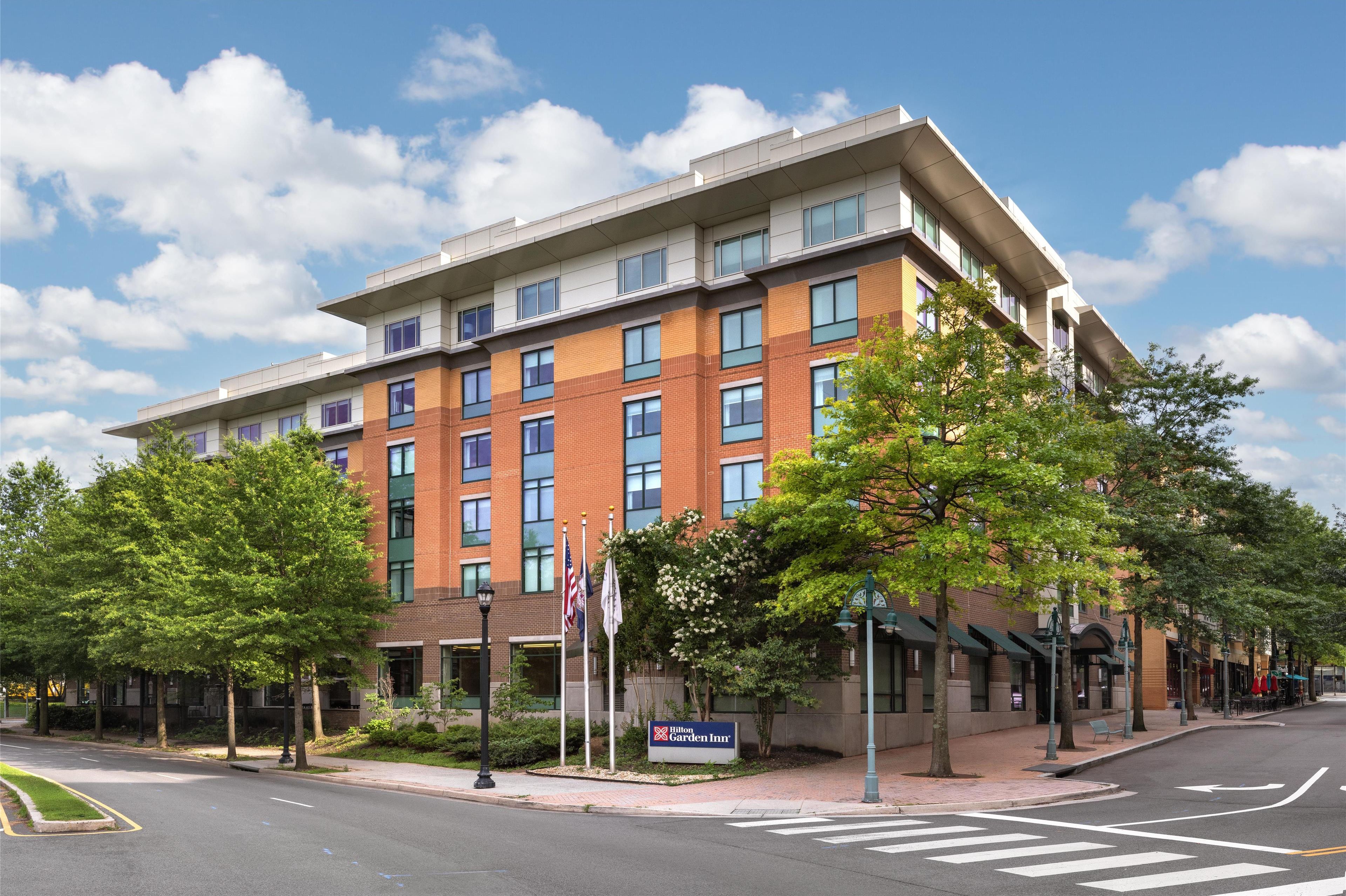 A multi-story hotel with a brick facade, large windows, and a sign indicating it is the Blue Garden Inn.