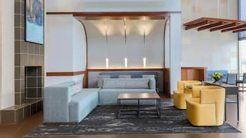 A modern lobby with a sectional sofa, a coffee table, and yellow armchairs.